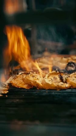 Chicken pieces grilling over open flames, highlighting the cooking process at the Mediterranean fine dining restaurant.