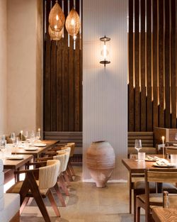 Mediterranean fine dining restaurant interior with wooden furniture, warm lighting, and a large decorative clay pot.