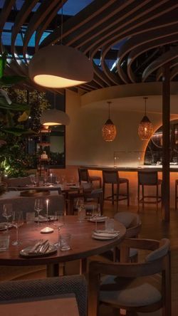 Dining area of a fine dining Mediterranean restaurant with wooden tables, ambient lighting, and a stylish ceiling design.